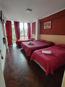 圣萨尔瓦多德朱Hotel Ery Noa的宿舍间的三张床,设有红色的墙壁和窗户