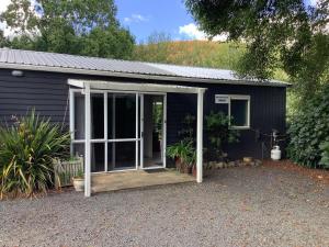 WaikinoWood Pigeon Cottage Pet Friendly Free Breakfast Hauraki Rail Trail 2kms的一个小黑棚,有一扇门打开