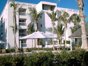 格雷斯湾Le Vele Resort的一座白色的建筑,种植了棕榈树,配有遮阳伞
