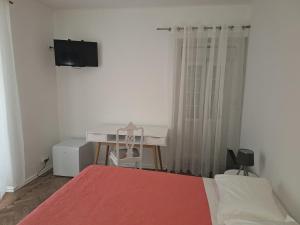 辛特拉Penaferrim Sintra Rooms的一间卧室配有一张床、一张书桌和一台电视