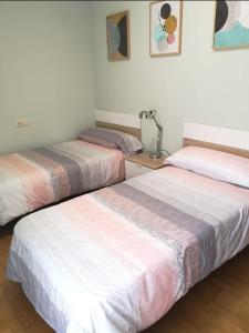 阿尔内迪略Apartamento las huellas的配有3张床铺的白色和粉红色床单