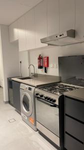 沙迦Al jada / Reef 4的厨房配有炉灶和洗衣机。