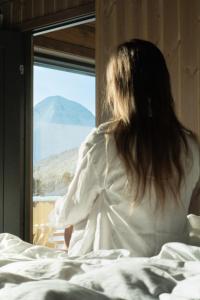 斯特兰达Unique Romantic Cabin with Mountain View at Strandafjellet, Mivo X的坐在床上,从窗户望出去的女人