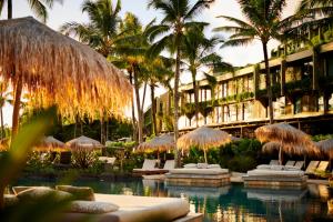 普林斯维尔1 Hotel Hanalei Bay的一个带遮阳伞和棕榈树的游泳池的度假酒店