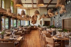 普林斯维尔1 Hotel Hanalei Bay的餐厅设有木桌、椅子和窗户。