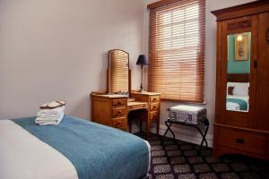 悉尼The Australian Heritage Hotel的一间卧室配有一张床和一张带镜子的书桌