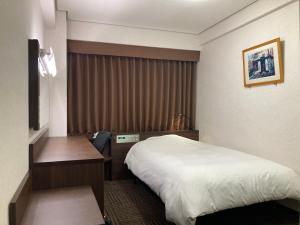 山口Hotel Alpha-One Ogori的配有一张床和一张书桌的酒店客房