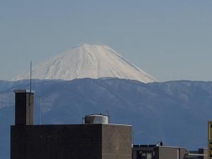 甲府ユースホステルソノママ的一座建筑物后面的雪覆盖的山