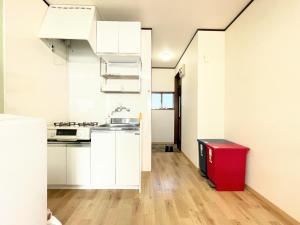 东京House Kadoi201的厨房配有白色橱柜和红色垃圾桶