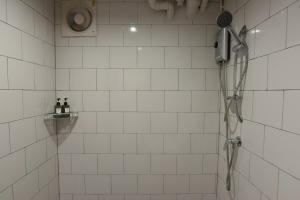 北碧V1 boutique hotel的白色瓷砖浴室内的淋浴和吹风机