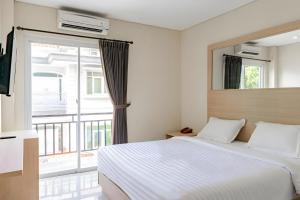库塔Super OYO Airport Kuta Bali Hotel的一间卧室设有一张床和一个大窗户