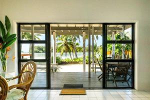 拉罗汤加穆里泻湖碧斯海滨度假屋的一间设有滑动玻璃门和桌子的用餐室