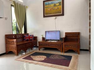 玛琅Villa Murah Malang的客厅配有2张木制家具和电视