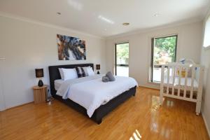 HallCanberra Comfort Family Cottage with 5 Beds& Pet Welcoming的一间卧室配有一张带白色床单的大床