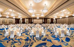 温州温州香格里拉的一间设有桌椅的大型宴会厅,位于一间蓝色地毯的房间内