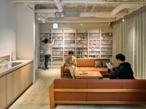 川崎Hotel Plus Hostel TOKYO KAWASAKI的两个人坐在图书馆的沙发上