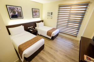 宿务Cebu Quincentennial Hotel的酒店客房设有两张床和窗户。