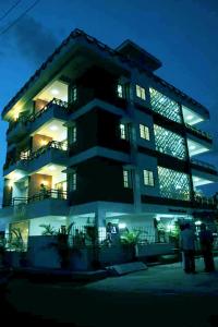 班加罗尔ZIONS AIRPORT HOTEL AND APERTMENT! Near Kempegowda International Airport的一座建筑,人们在晚上站在它前面