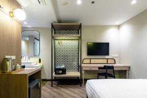 曼谷The Cotton Saladaeng Hotel的酒店客房配有一张床、一张书桌和一台电视。
