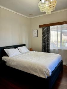诺瑟姆Charming Brick Homestay Room in Northam的一间卧室配有一张大床和一个吊灯。