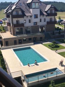 兹拉蒂博尔Zlatibor Hills Apartments Wellness & Spa的两人坐在房子前面的游泳池里
