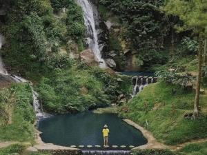 玛琅Villa Estetis di Kota Batu的站在瀑布前的桥上的人