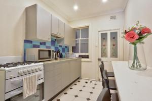 悉尼Affordable 3 Bedroom House Darlinghurst with 2 E-Bikes Included的厨房配有白色橱柜和玫瑰花瓶