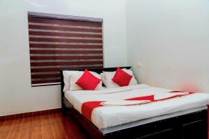 维特利pookode villa的一间卧室配有一张带红色枕头的床