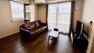 鹿儿岛Apartment Hotel Ecott的客厅配有真皮沙发和电视