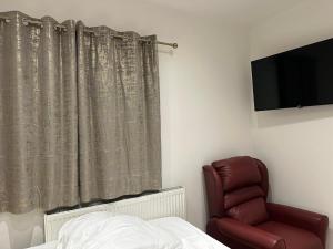 布罗姆利2nd Studio Flat With Great Views in Keedonwood Road With Private Kitchenette and shared bathroom的一间卧室配有一张床、一把椅子和电视