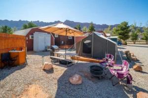 摩押Moab RV Resort Glamping Setup Tent in RV Park #4 OK-T4的一个带电视、椅子和遮阳伞的帐篷