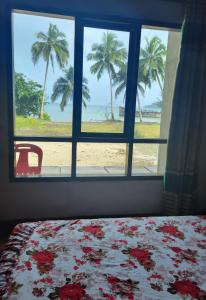TelukdalemTaman Baloho Indah - Hotel & Resort的一间卧室设有窗户,享有海滩美景