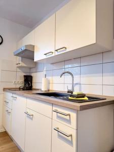 OesterdeichstrichSchönes 1-Zimmer-Appartement, Büsum (4km) Nordsee的厨房配有白色橱柜和水槽