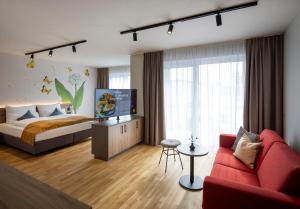 巴特拉德克斯堡JUFA Hotel Bad Radkersburg - inkl 4h Thermeneintritt的一间卧室配有一张床和一张红色的沙发