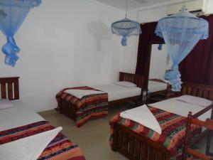 韦勒沃耶Saranga Holiday Inn的带三张床和镜子的客房