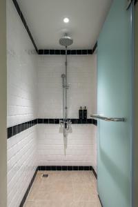 曼谷The Cotton Saladaeng Hotel的浴室铺有黑白瓷砖,设有淋浴。