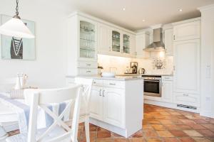 曼克玛肖Haus Moin的厨房配有白色橱柜和桌子