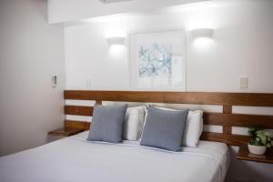 道格拉斯港Port Douglas Peninsula Boutique Hotel - Adults Only Haven的卧室配有带蓝色枕头的大型白色床