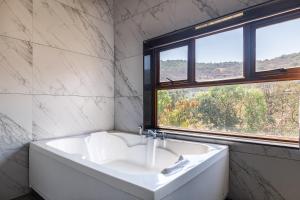 罗纳瓦拉Hillside Resort Lonavala - Pawna - Mountain View的带窗户的浴室内的白色浴缸