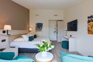 圣拉斐尔Golf Hôtel de Valescure & Spa NUXE的配有床和鲜花桌的酒店客房