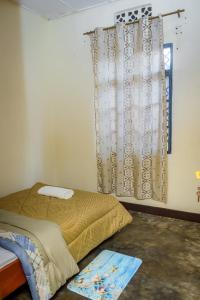鲁亨盖里Rhoja homes的一间卧室配有一张带窗帘的床和窗户