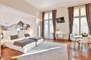 萨尔拉拉卡内达La Villa des Consuls - Gîte de tourisme de charme的白色卧室配有床和桌子