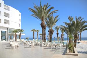 莫纳斯提尔Blue Beach Golf and Spa的一个带棕榈树和椅子的度假庭院