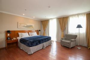 里约热内卢Flat Barra First的配有一张床和一把椅子的酒店客房