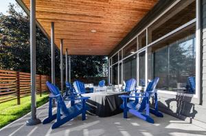 金斯顿Comfort Suites Kingston Central的露台设有蓝色椅子和门廊上的桌子