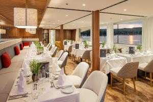 巴塞尔Thurgau Gold - Art Basel Riverboat Hotel I的一间设有白色桌子和白色椅子的餐厅
