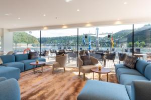 巴塞尔Thurgau Gold - Art Basel Riverboat Hotel I的大堂设有蓝色的沙发和桌子以及大窗户。