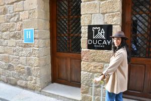 奥利特Ducay Rooms的站在建筑物前面的有标志的女人