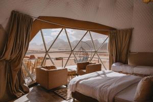瓦迪拉姆Shaheen Camp Wadi rum的一间卧室配有床和椅子以及大窗户