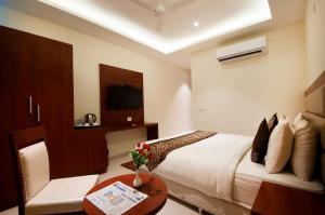 新德里Prime Z Suites Hotel- Near Delhi International Airport的一间酒店客房,配有一张床铺、一张桌子和一台电视